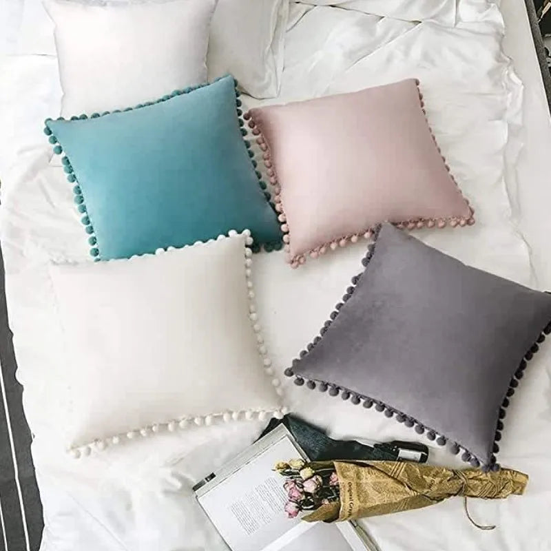 Canapé avec une housse de coussin en velours à pompons, un plaid doux et des bougies LED