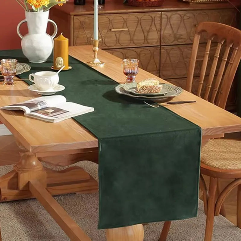 Table dressée avec un chemin de table en velours vert, des ronds de serviette dorés et des bougies LED sans flamme
